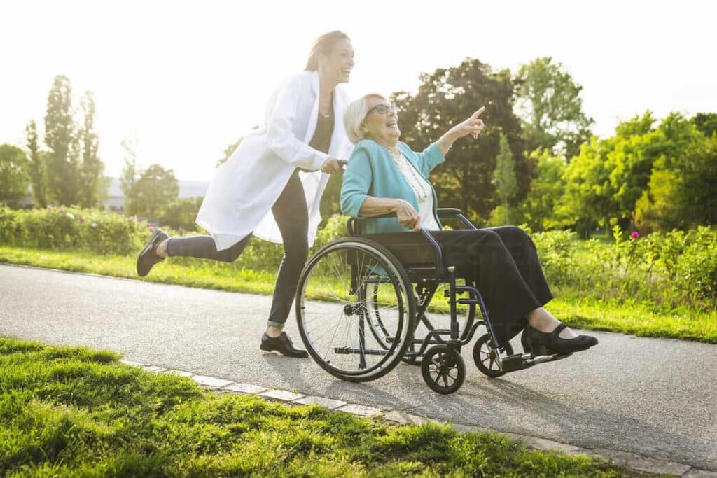 A woman in a wheelchair is being pushed by a doctor at home.