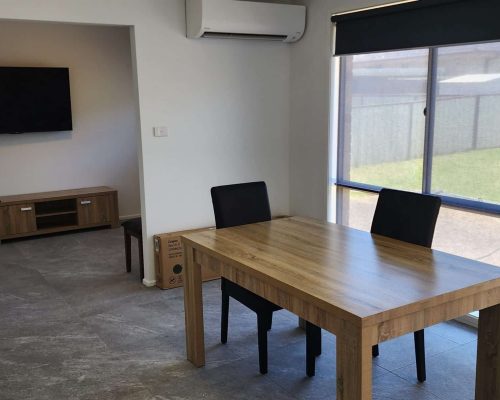 A room with a table and chairs and a tv.