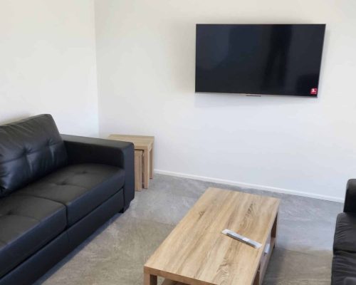 A living room with black leather couches and a tv.