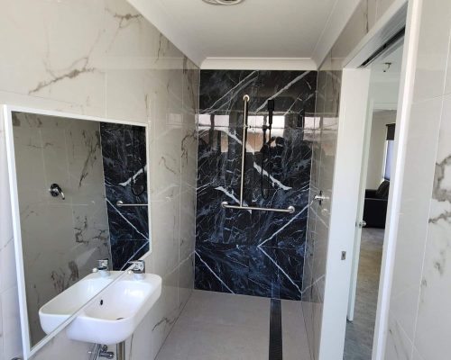 A bathroom with a black and white marble wall.