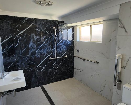 A bathroom with black marble walls and a toilet.