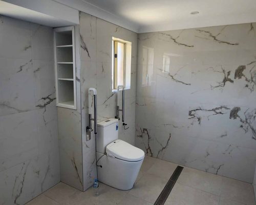 A bathroom with marble walls and a toilet.